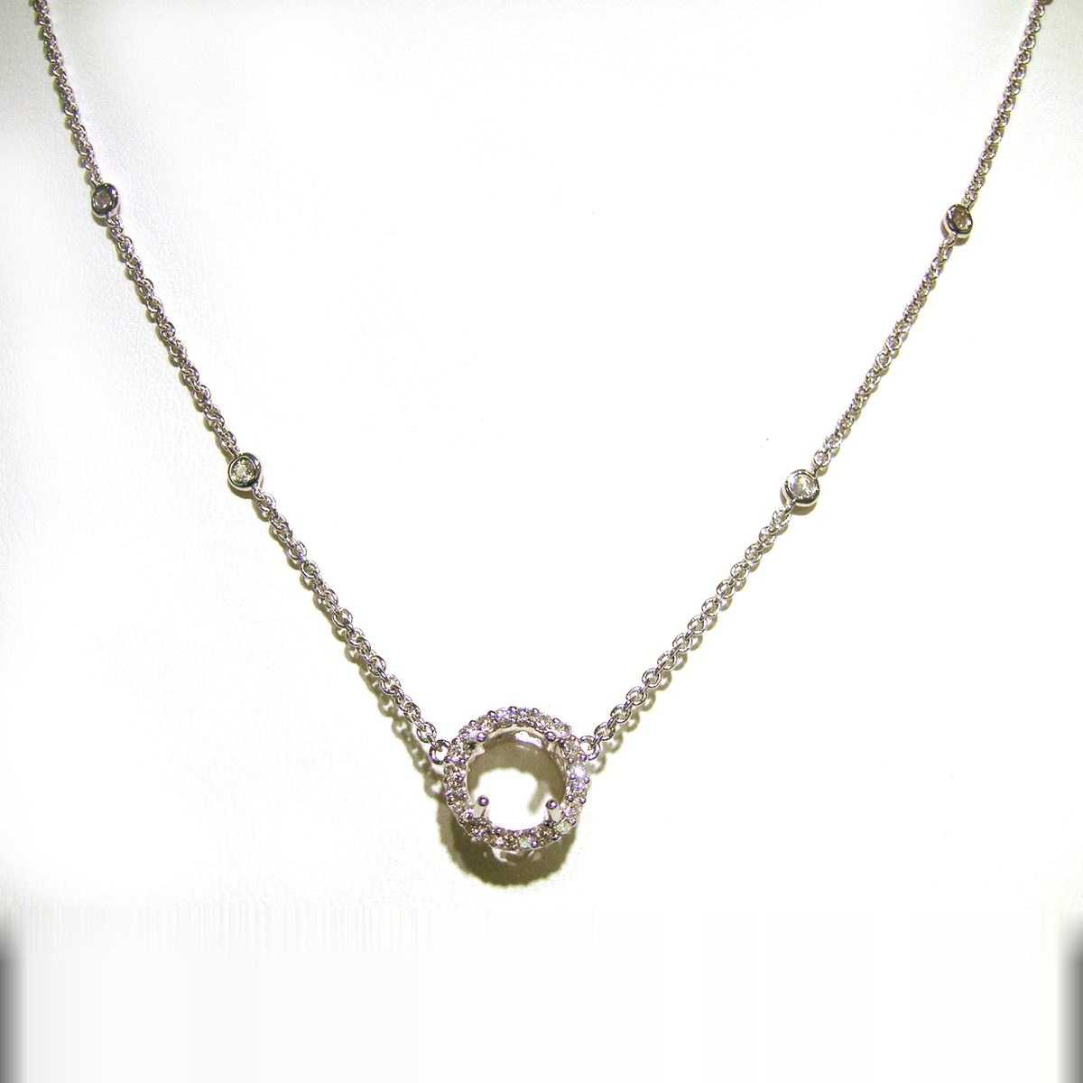 White gold necklace with a pave diamond halo pendant and bezel set stations