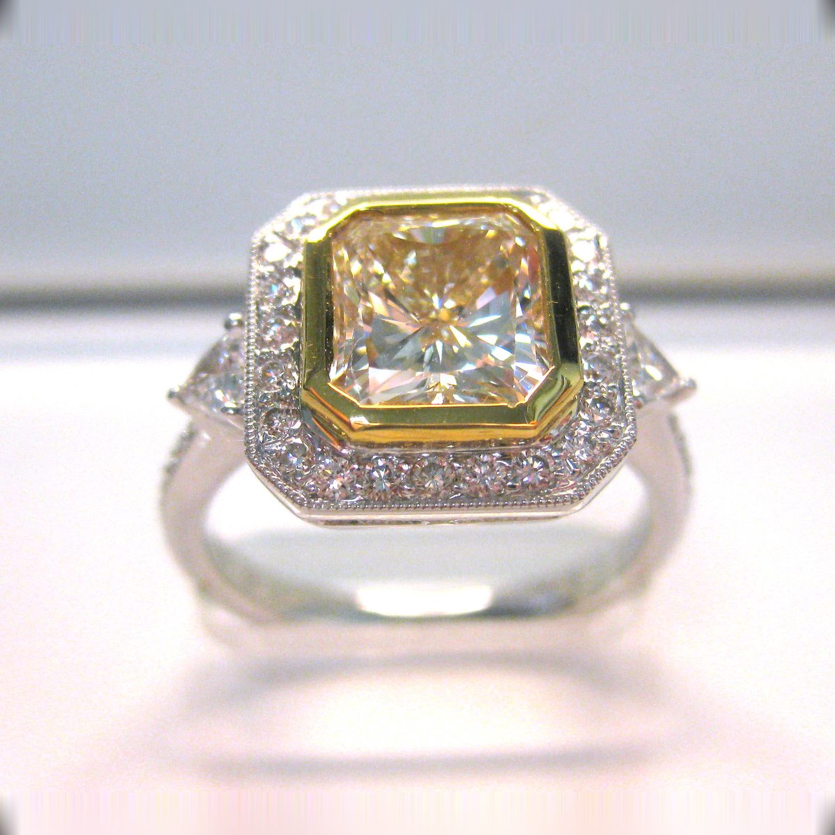 Fancy yellow radiant cut diamond ring with a pave halo and trapezoid side stones